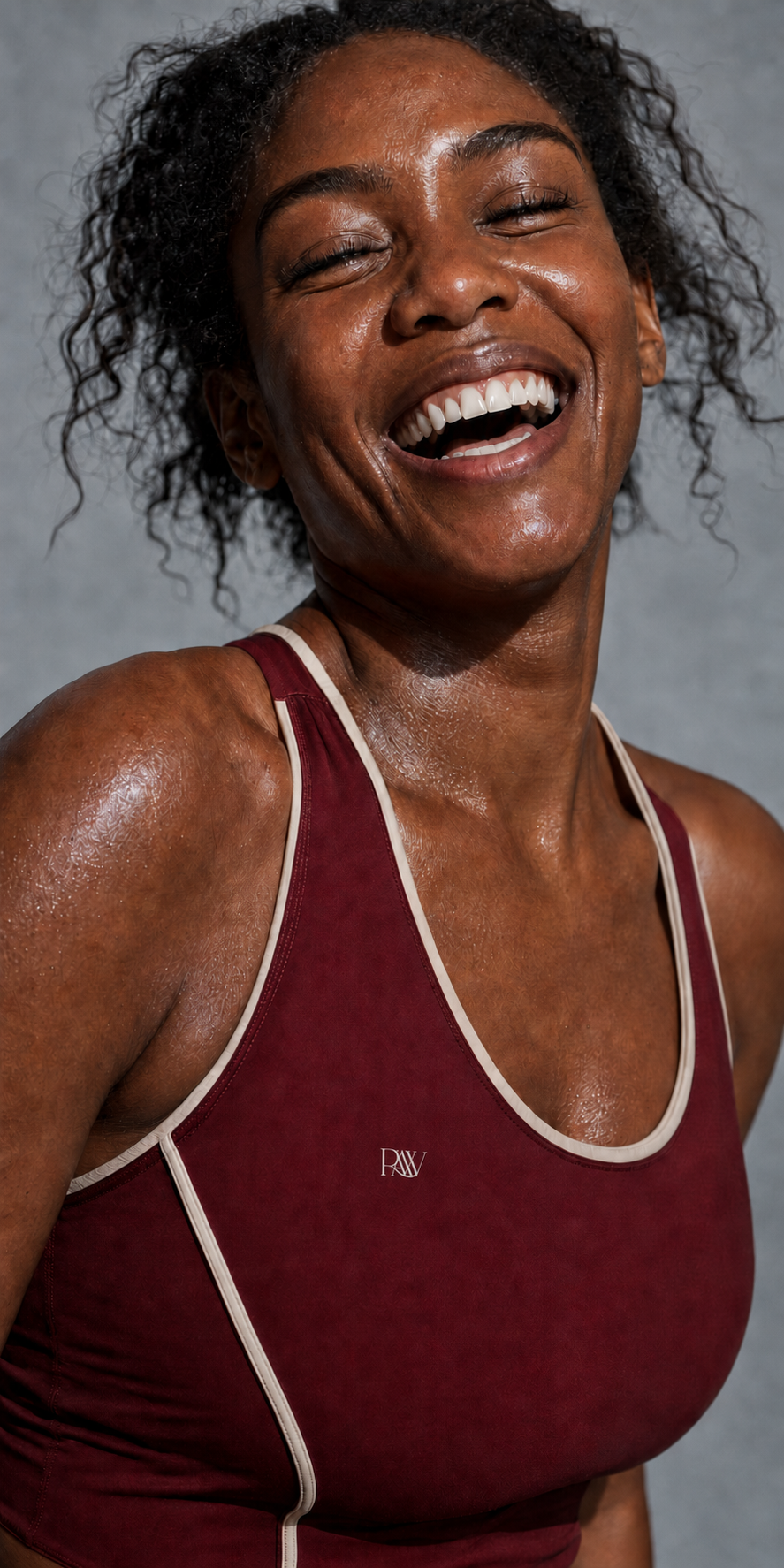 Joyful Black RAW athlete wearing a burgundy RAW fitness top after a workout